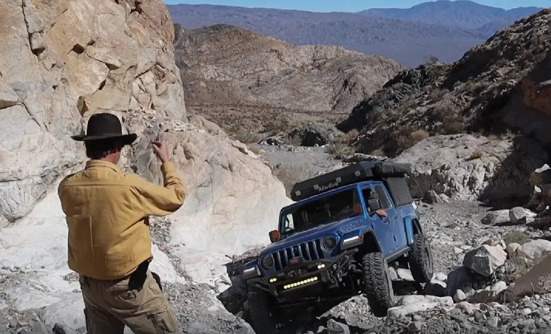 Getting directed on a tight line through a boulder field by a Jeep Rubicon 4x4 in Death Valley